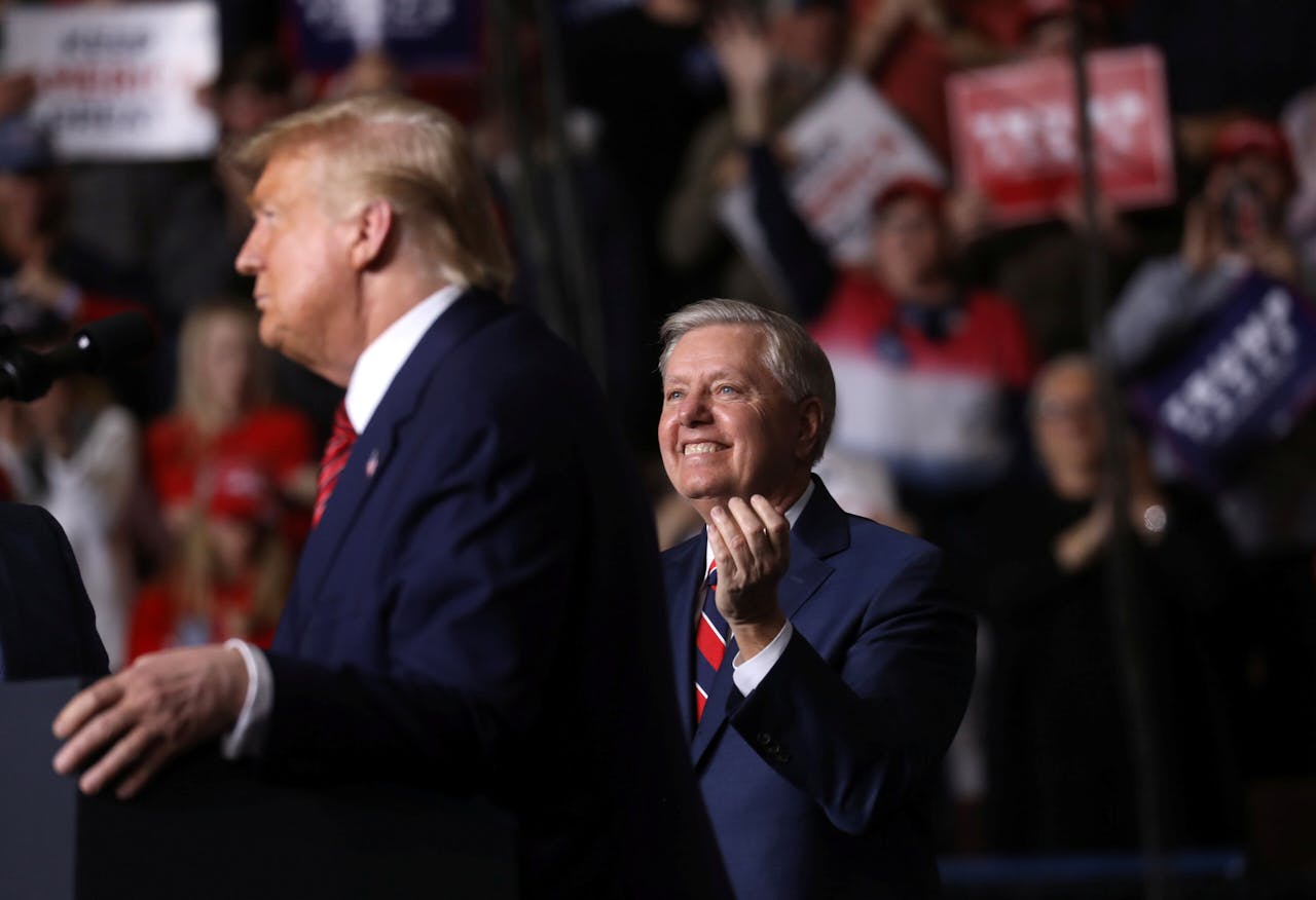Republikeins senator Lindsey Graham klapt voor Donald Trump tijdens een campagnebijeenkomst. Grahams loyaliteit aan Trump is voor een groep Republikeinen in South Carolina aanleiding niet meer op hem te stemmen. 